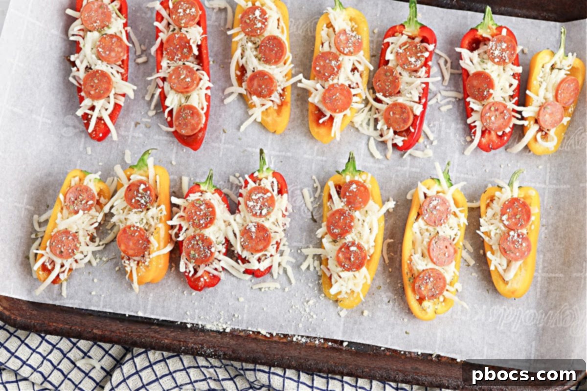 Adding shredded mozzarella cheese to mini bell pepper halves
