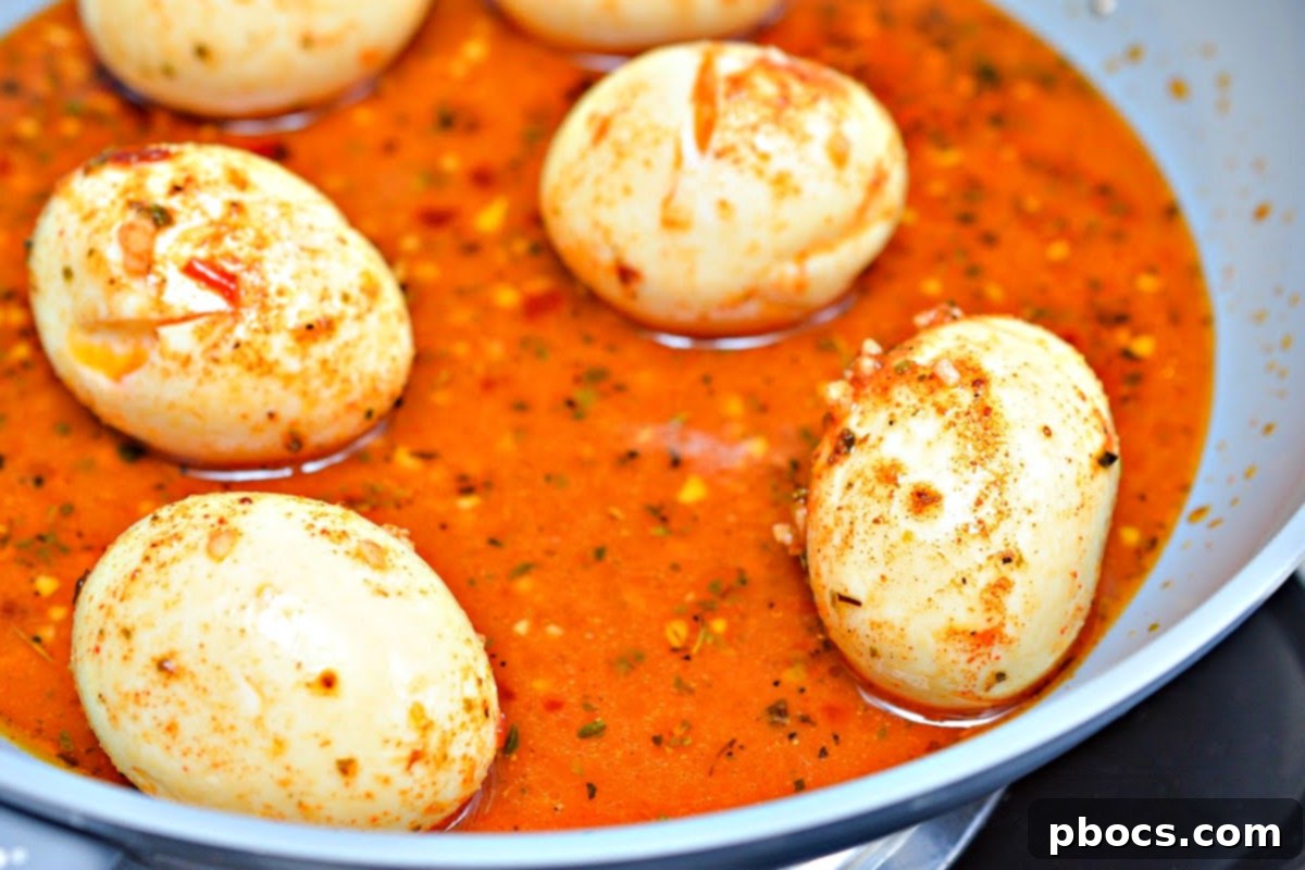 Hard-boiled eggs simmering in spicy keto sauce