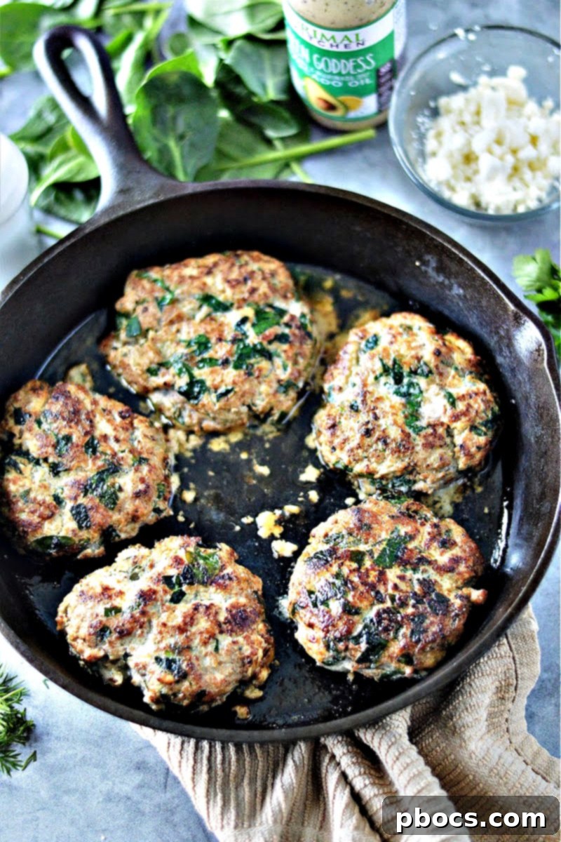 Searing Keto Spinach Feta Turkey Burgers in a hot skillet