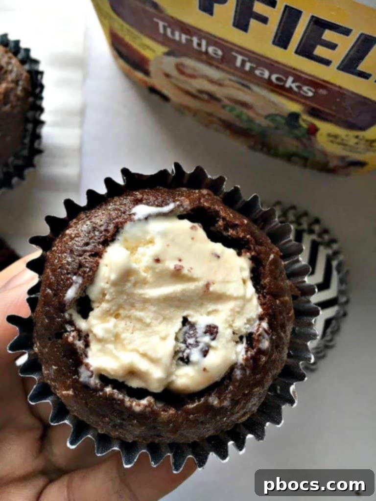 A cupcake being filled with a scoop of Mayfield® Turtle Tracks ice cream