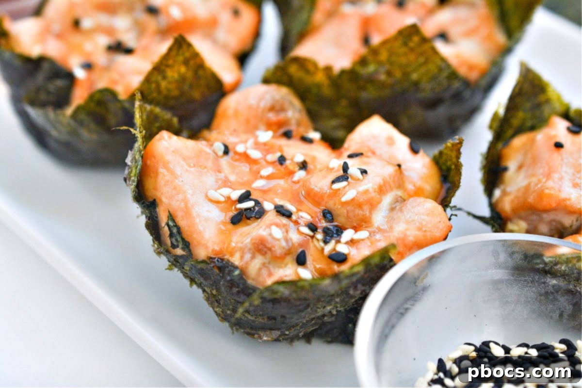 Four salmon sushi nori cups arranged artfully on a white plate