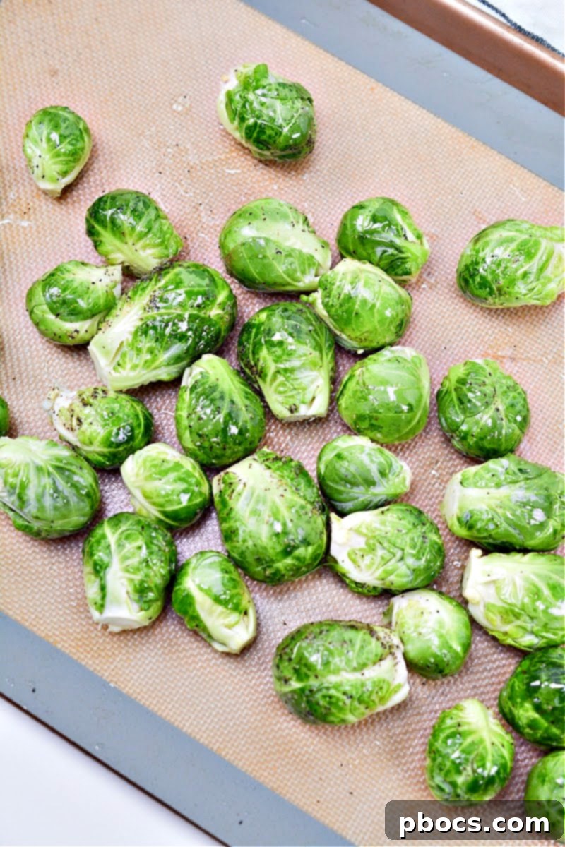 Raw, trimmed Brussels sprouts neatly arranged on a baking sheet lined with parchment paper, ready for roasting.