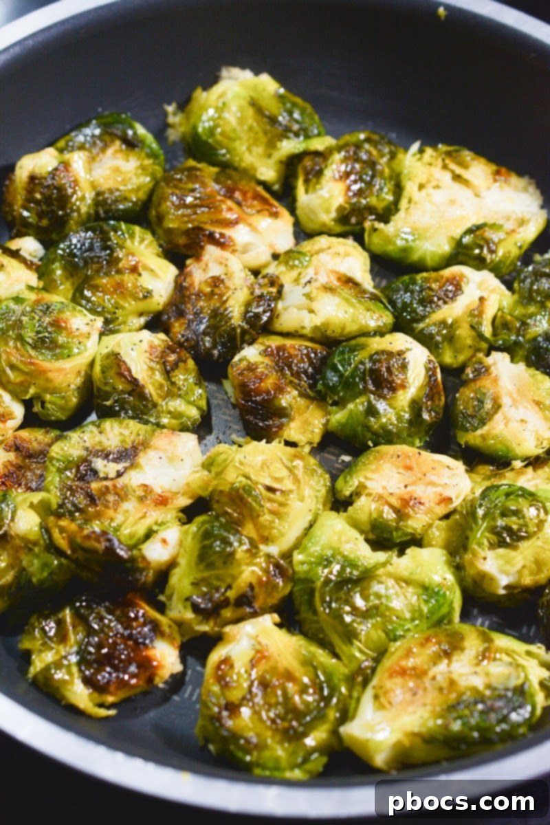 Smashed Brussels sprouts arranged in a hot skillet, preparing to be drenched in brown butter and sautéed to perfection.