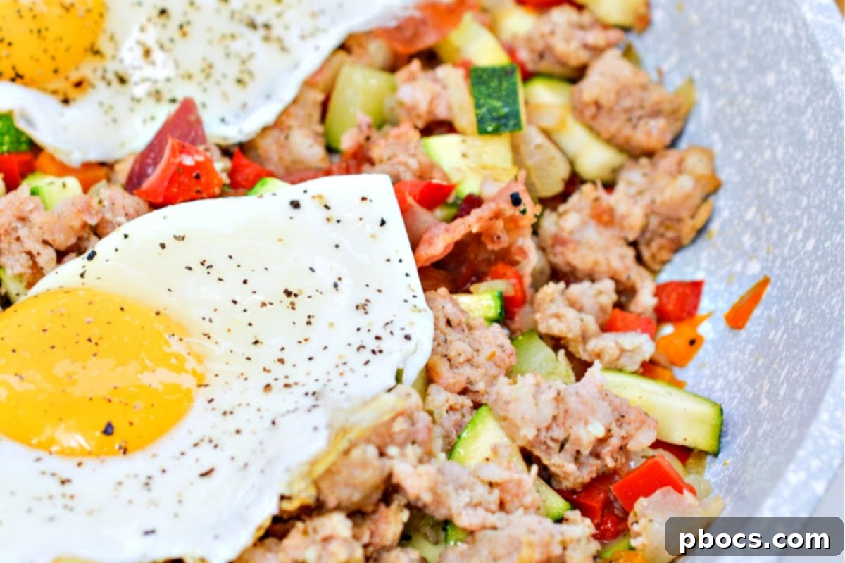 Keto Sausage Zucchini Breakfast Skillet 11 Two perfectly fried eggs gently placed on top of a serving of Keto Zucchini Breakfast Hash, ready to be enjoyed.