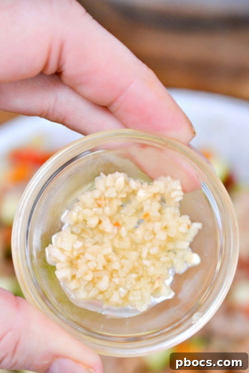 Keto Sausage Zucchini Breakfast Skillet 10 A small bowl containing minced garlic, prepared to be added to the hash for enhanced flavor.