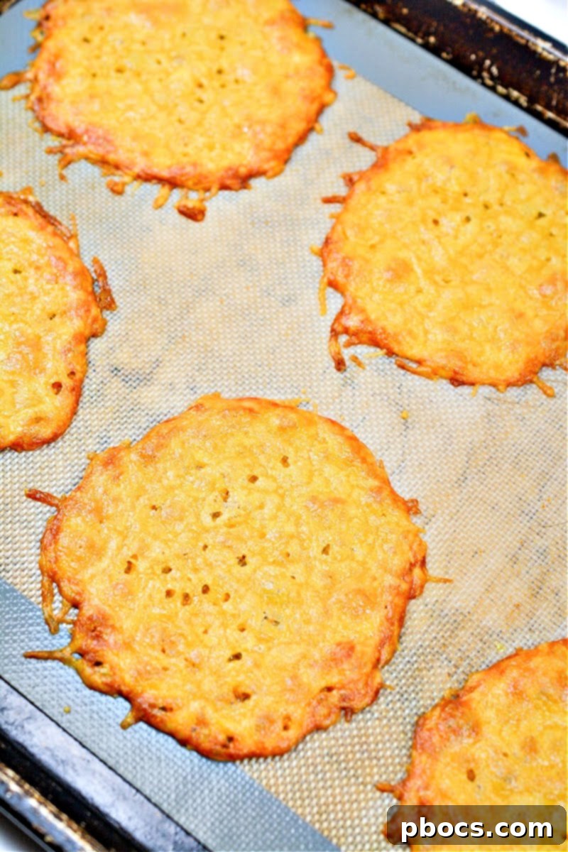 Eight baked cheese wraps cooling on a parchment-lined baking sheet, golden and crispy at the edges.