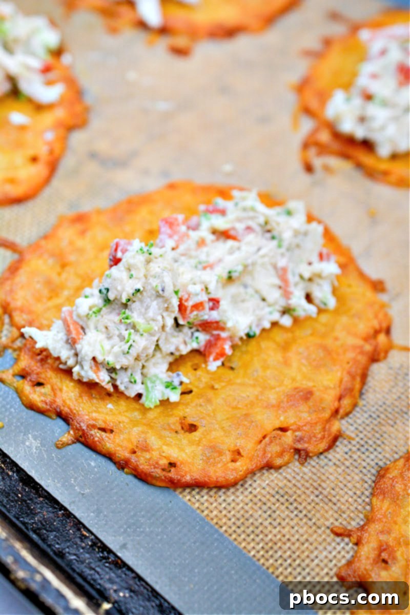 A Keto Ranch Cream Cheese Chicken and Veggies Roll Up being formed, with filling placed on a warm cheese circle.