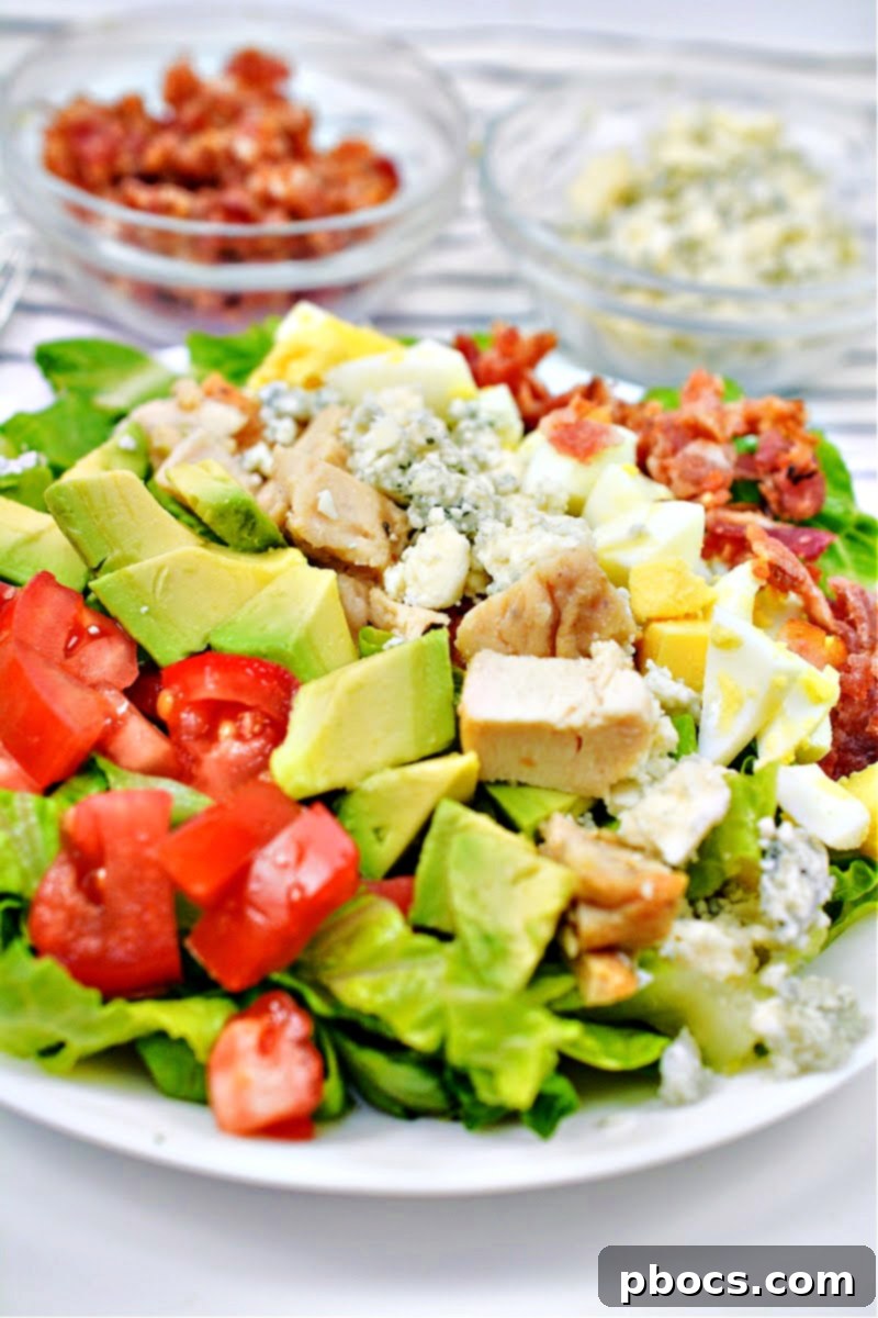 Keto Cheesecake Factory Chopped Salad on a white plate in front of a bowl of bacon
