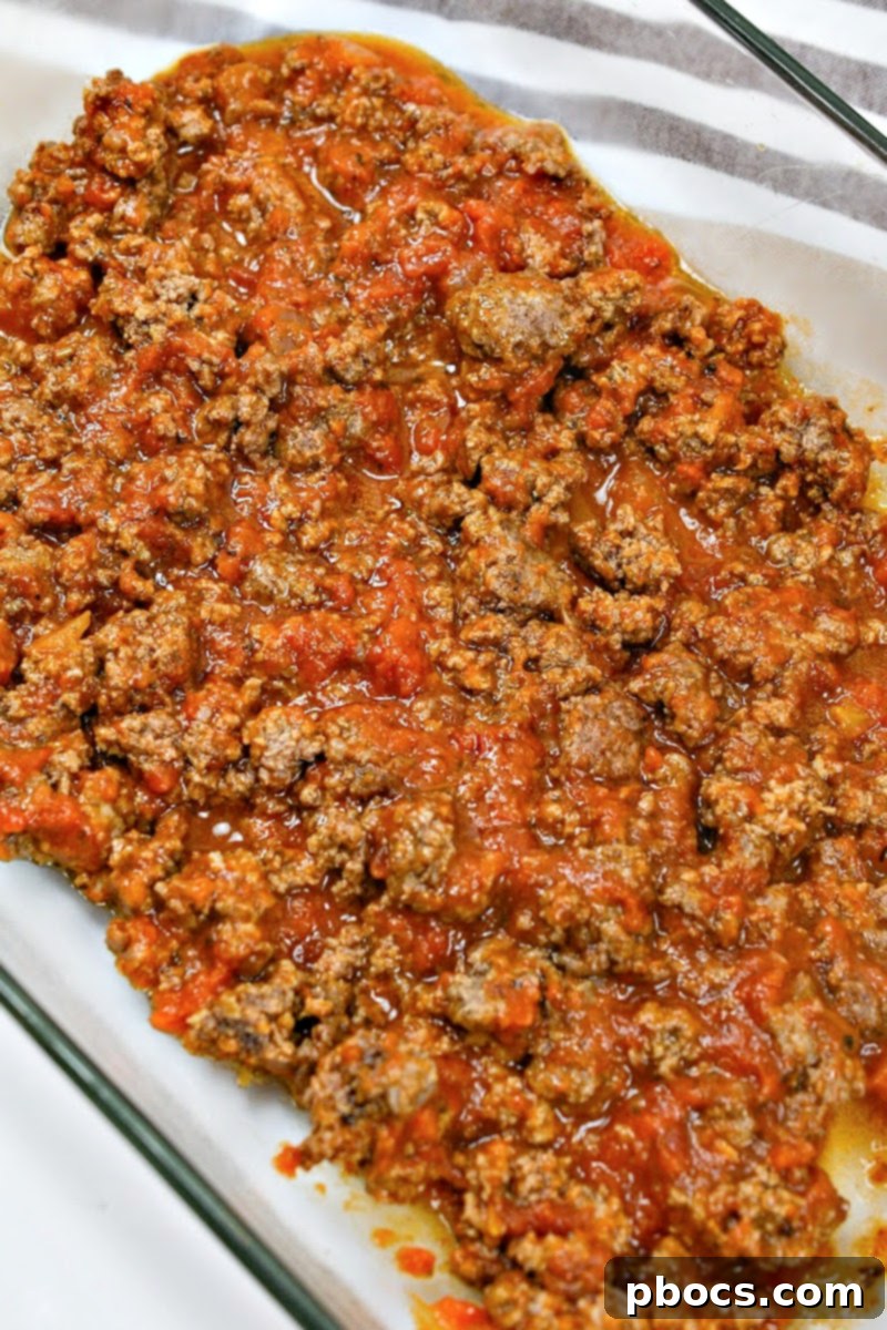 Preparing a baking dish with the first layer of meat sauce for Keto Protein Lasagna