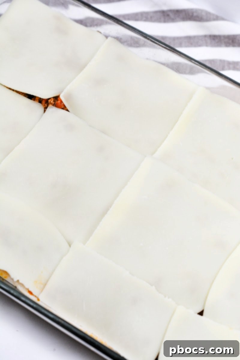 Adding a final layer of mozzarella cheese slices on top of Keto Protein Lasagna before baking