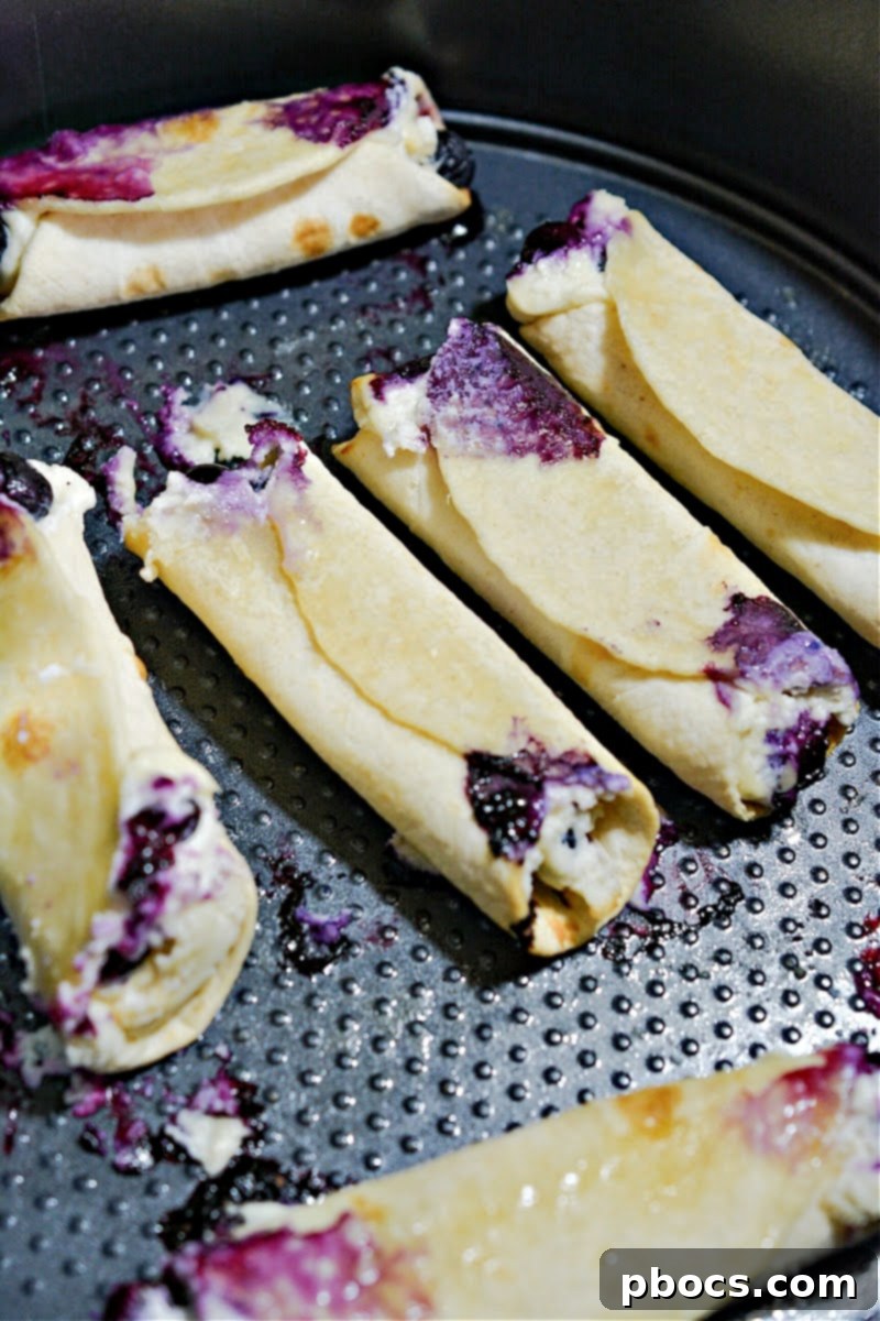 Crispy Keto Blueberry Cream Cheese Roll-Ups baking in the air fryer