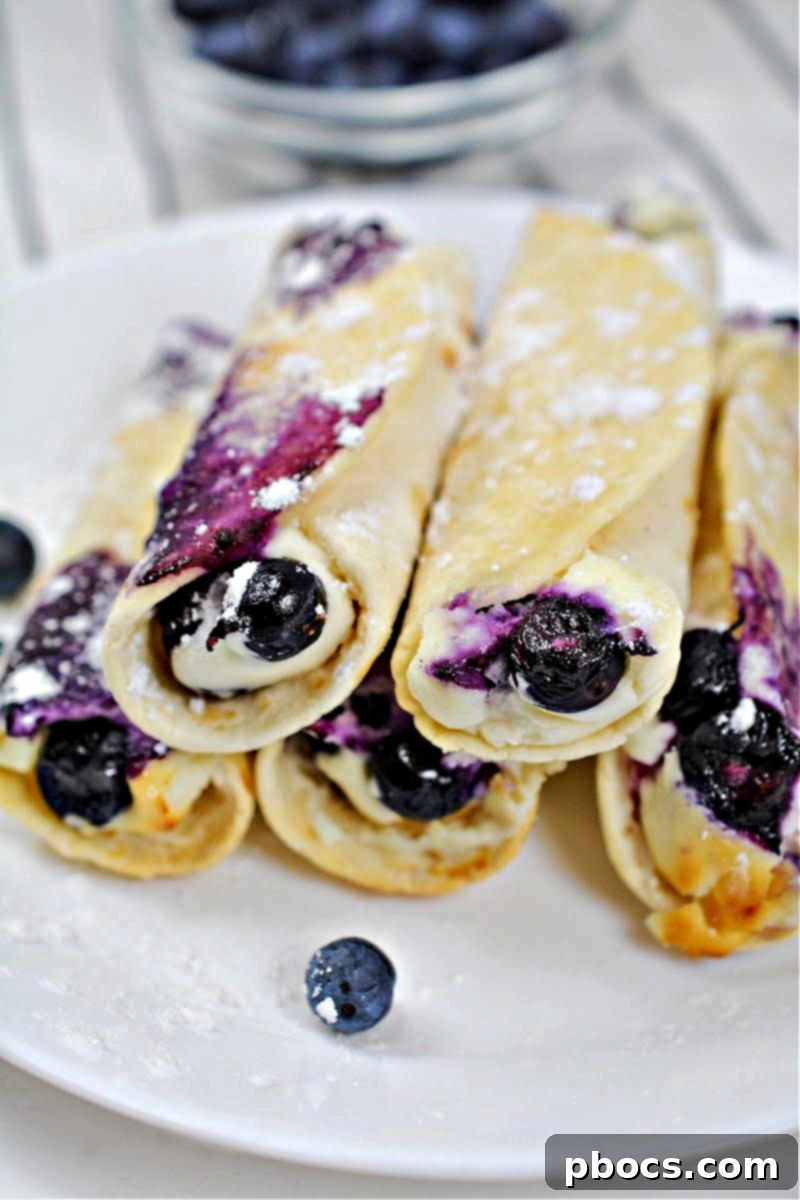 Five Crispy Keto Blueberry Cream Cheese Roll-Ups on a rustic wooden board