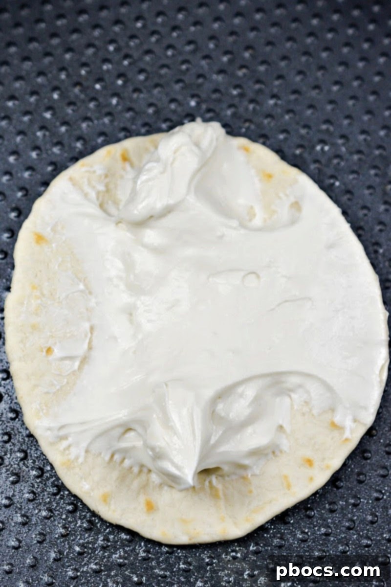 Spreading the cream cheese mixture onto a keto tortilla