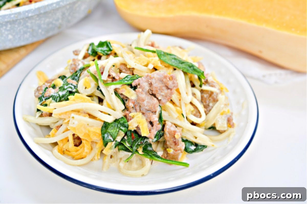 A serving of Low-Carb Butternut Squash Palmini Noodles With Sausage garnished with fresh parsley.