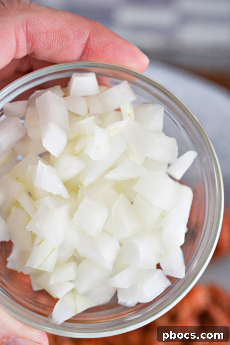 Finely diced onion on a cutting board, ready for sautéing.