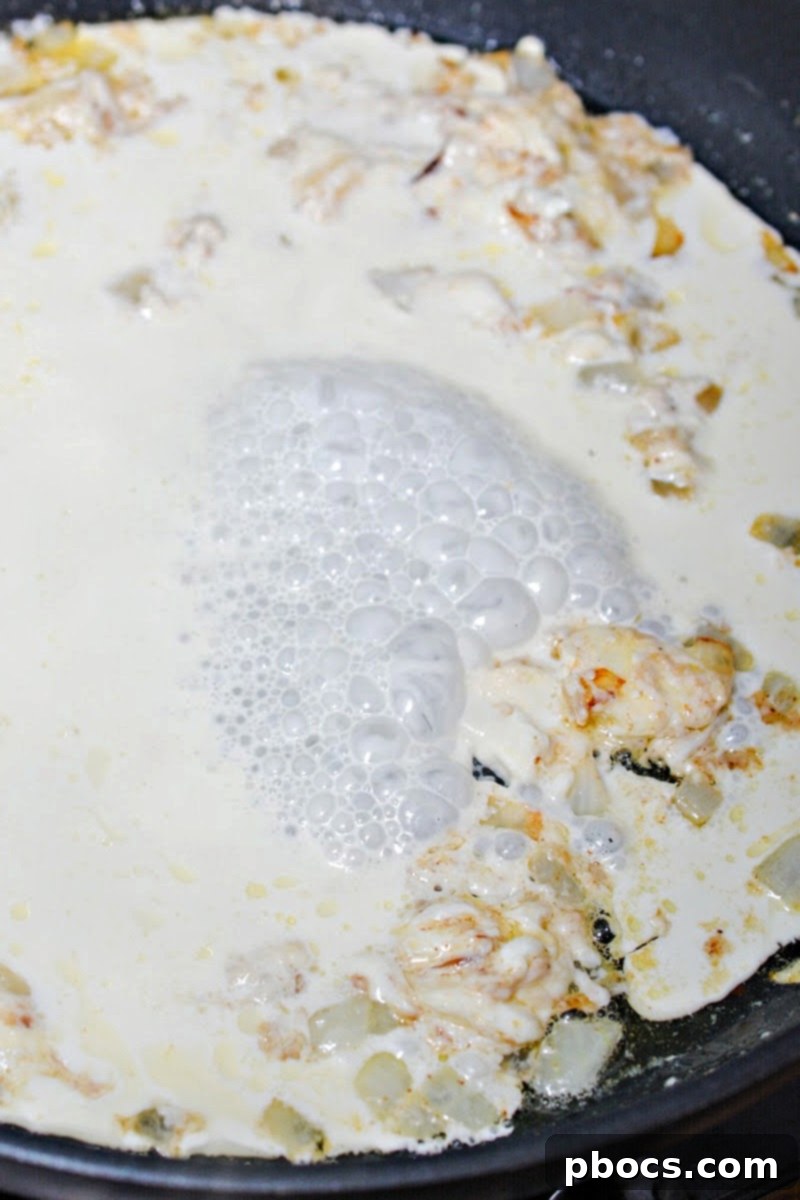Heavy cream bubbling gently in a skillet, thickening into a creamy sauce.
