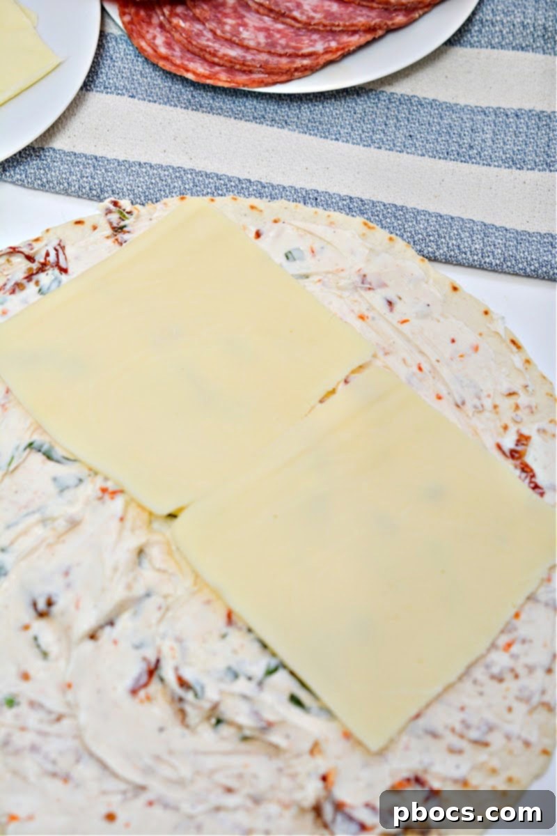 Keto Italian Swirls 12 Placing mozzarella cheese slices onto the cream cheese spread on a tortilla.