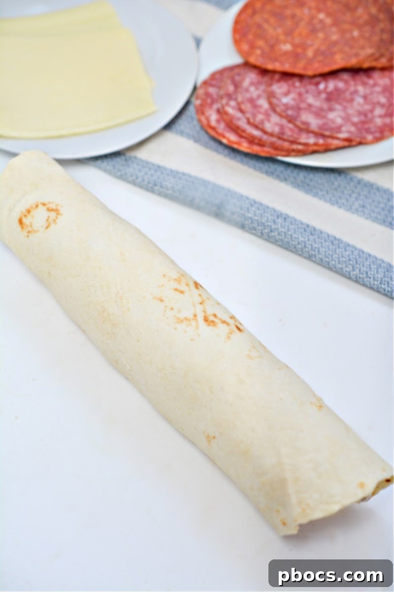 Keto Italian Swirls 14 Tightly rolling the filled tortilla into a log shape.