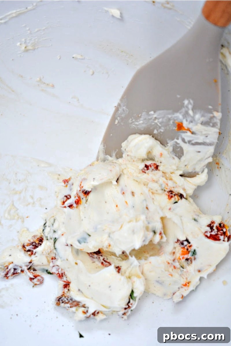 Keto Italian Swirls 10 Mixing cream cheese with sun-dried tomatoes and basil in a bowl.