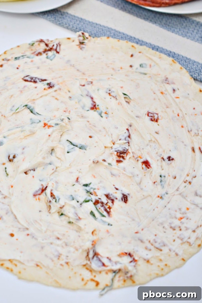 Keto Italian Swirls 11 Spreading the cream cheese mixture evenly over a keto tortilla.