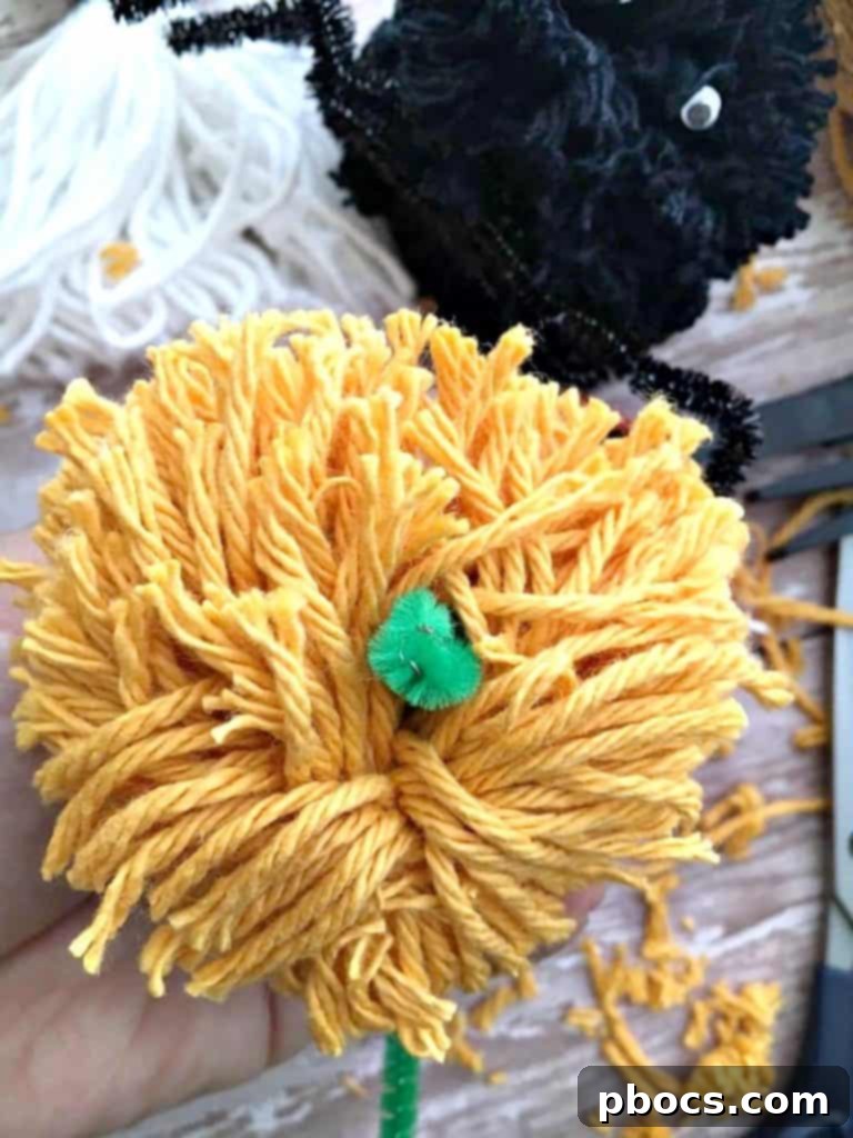 Adding a green pipe cleaner stem to a pom pom pumpkin