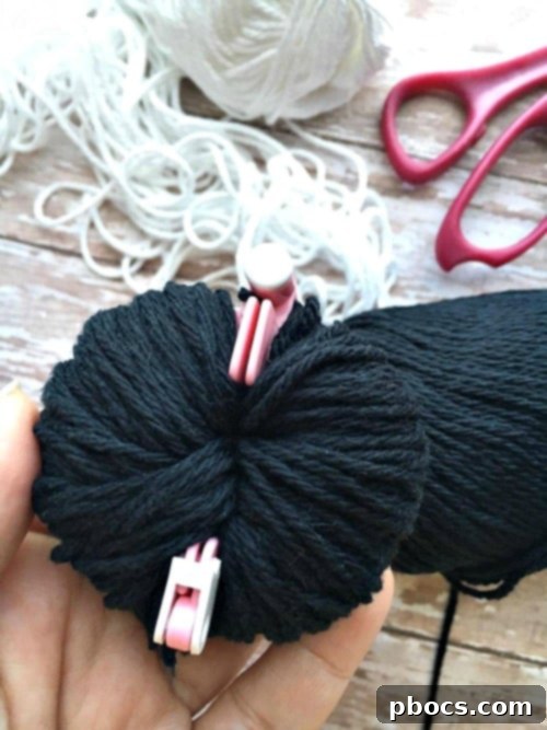 Cutting yarn along the pom pom maker's groove