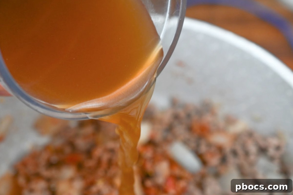 Simmering beef broth with the seasoned ground beef and turnip mixture