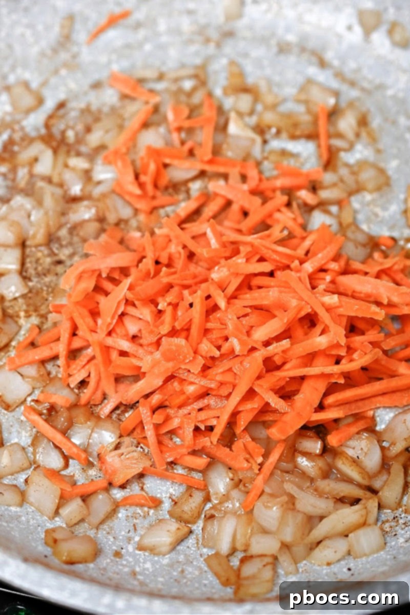 Matchstick carrots being added to the skillet with onions