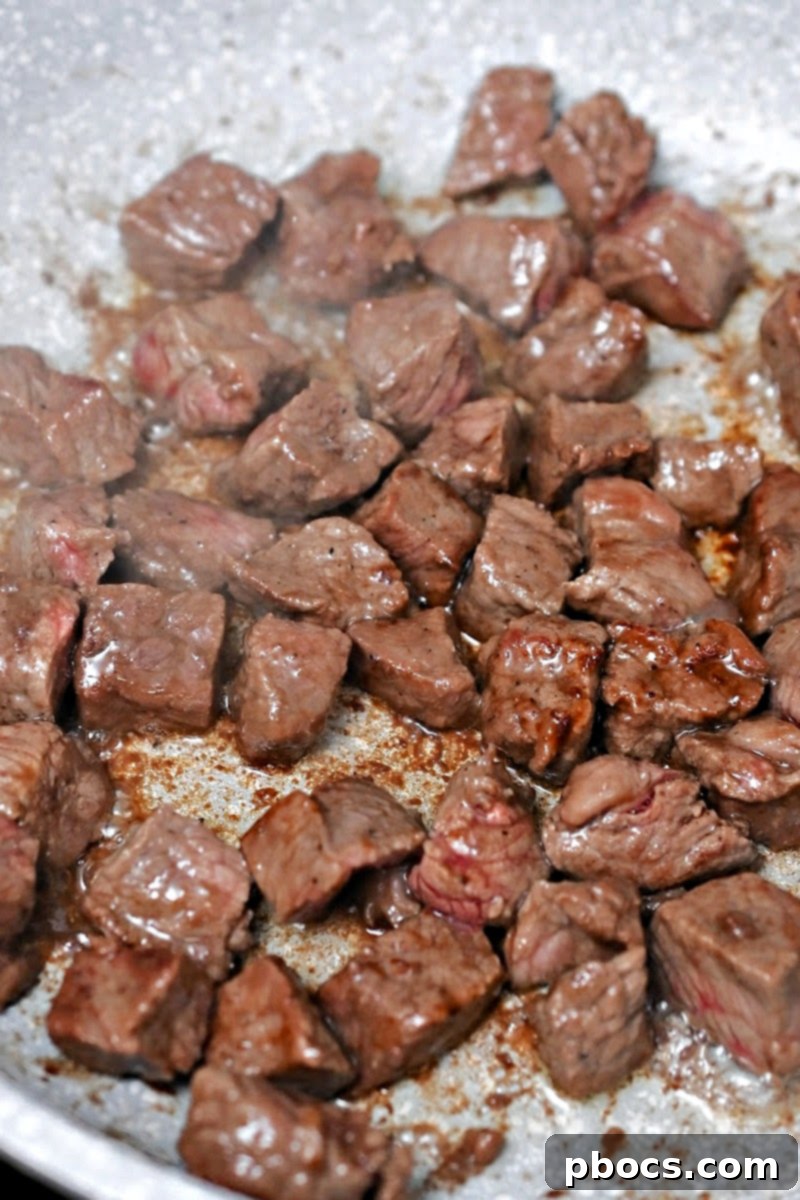 Beef being fried in a skillet with olive oil