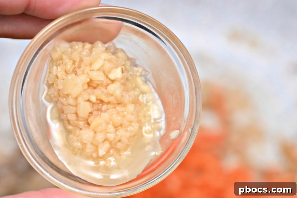 Minced garlic being added to a skillet