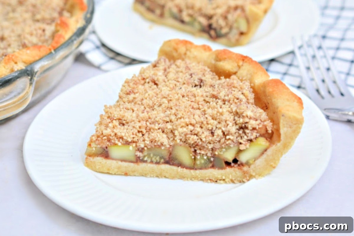 A slice of Keto Apple Pie on a white plate, showcasing the zucchini filling and golden crumble topping.