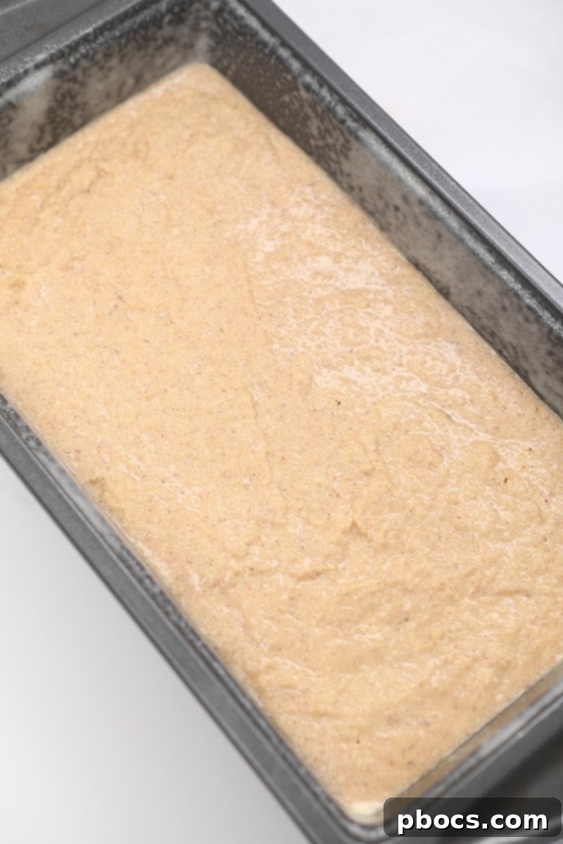 Pouring the smooth gingerbread loaf batter into the prepared loaf pan.