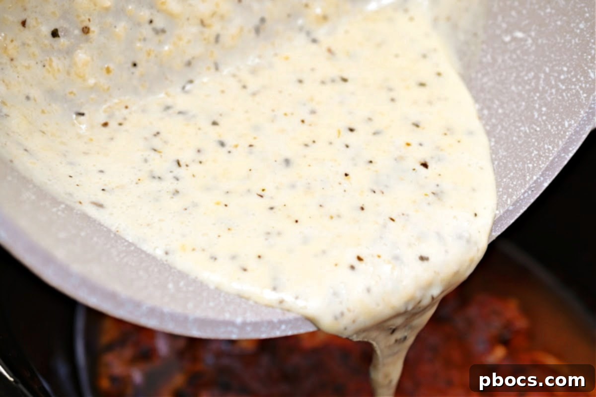 Keto Crockpot Tomato Alfredo Chicken, combining sauces.