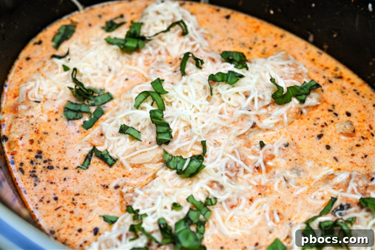Keto Crockpot Tomato Alfredo Chicken, garnished with melted mozzarella.