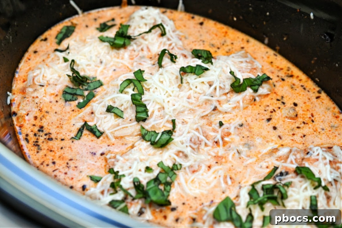 Keto Crockpot Tomato Alfredo Chicken, showcasing whole chicken breasts in a vibrant marinara.