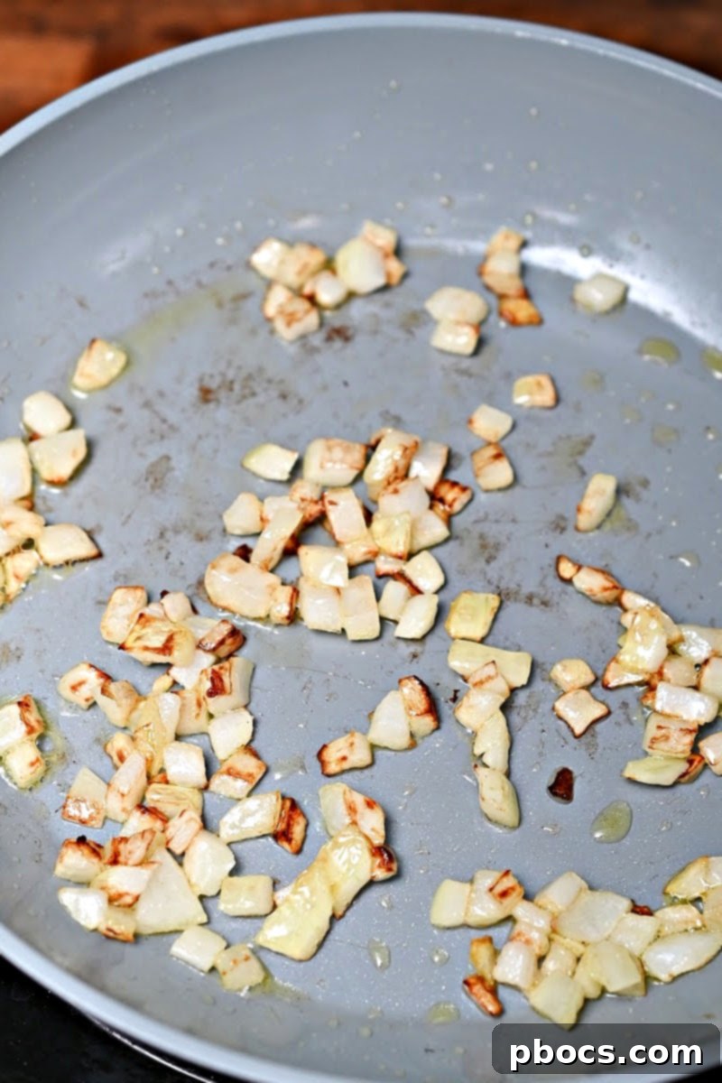 Chopped onion sautéing in a skillet with olive oil