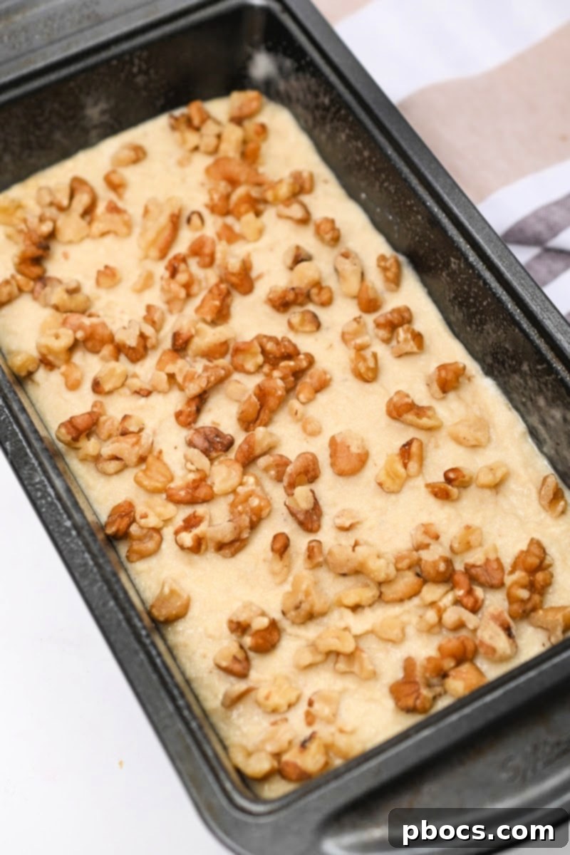 Creamy Low-Carb Ricotta Banana Bread 11 Walnuts being sprinkled on top of banana bread batter in a loaf pan