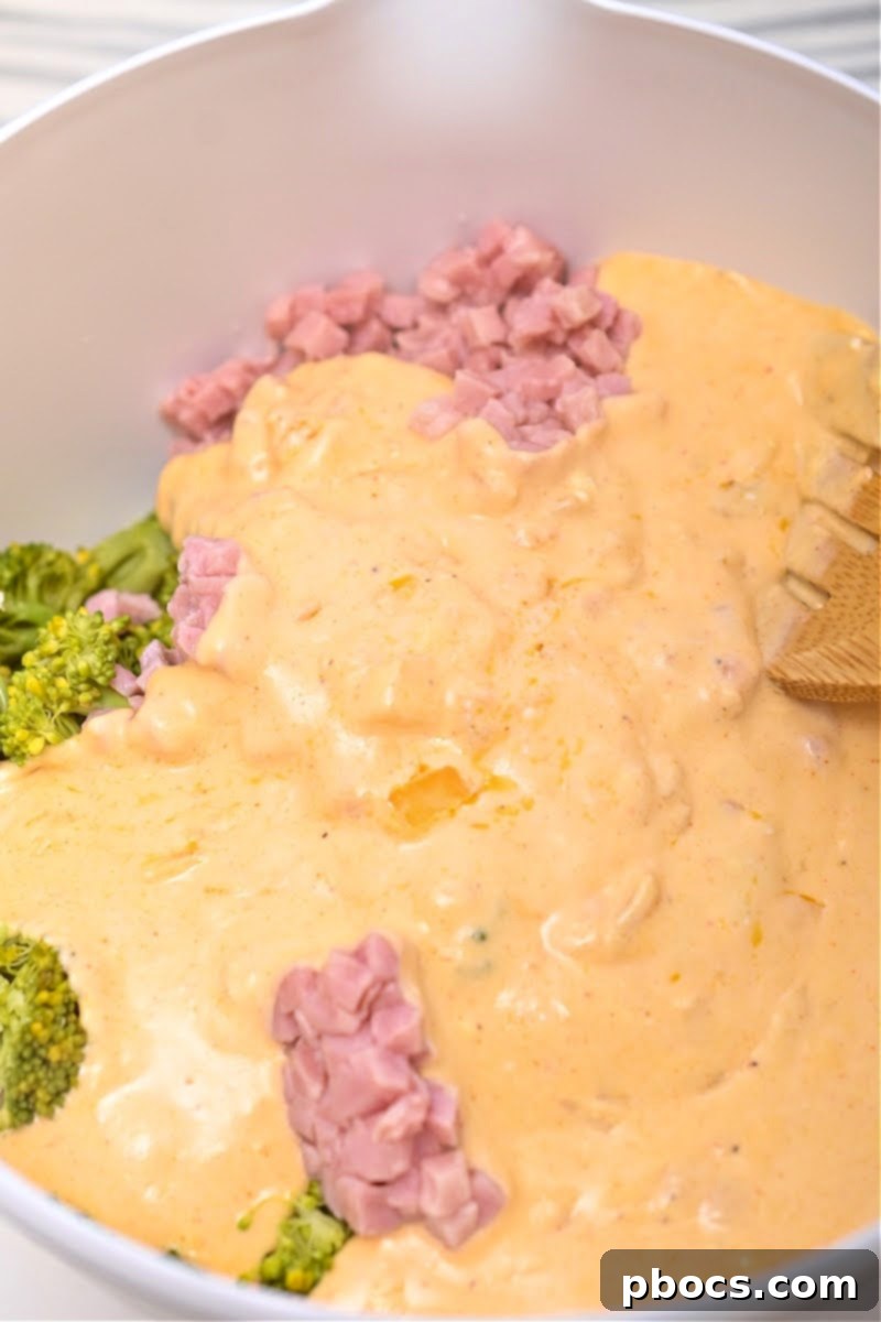 Combining cauliflower rice, broccoli, and ham in a bowl