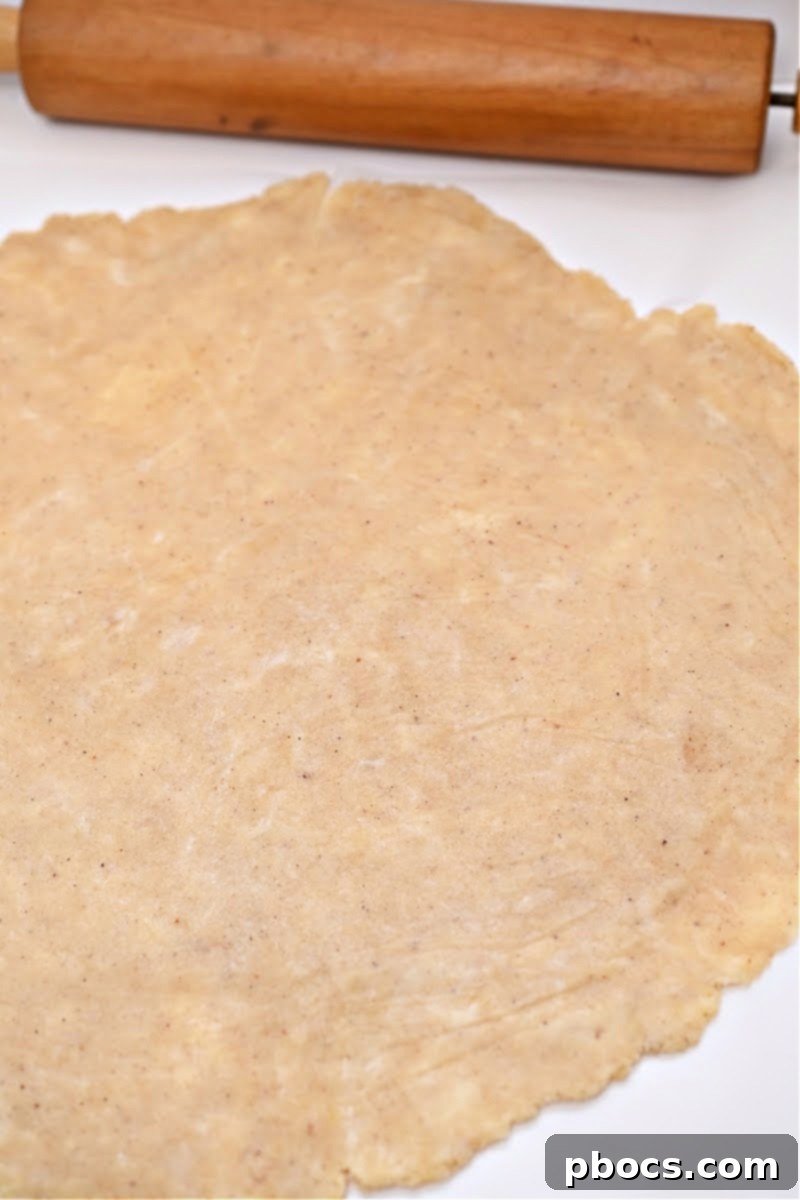 Rolling out the chilled keto crescent roll dough between two sheets of parchment paper to achieve even thickness.