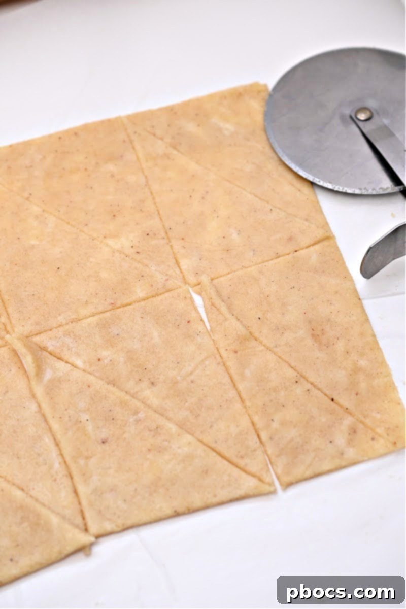 Precisely cutting the rolled-out keto crescent roll dough into small triangles, ready for filling and shaping.