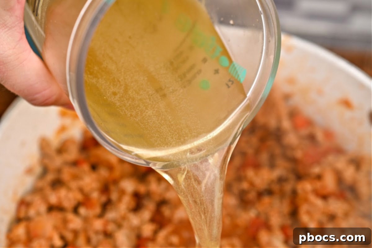 Chicken broth being poured into the chili pot