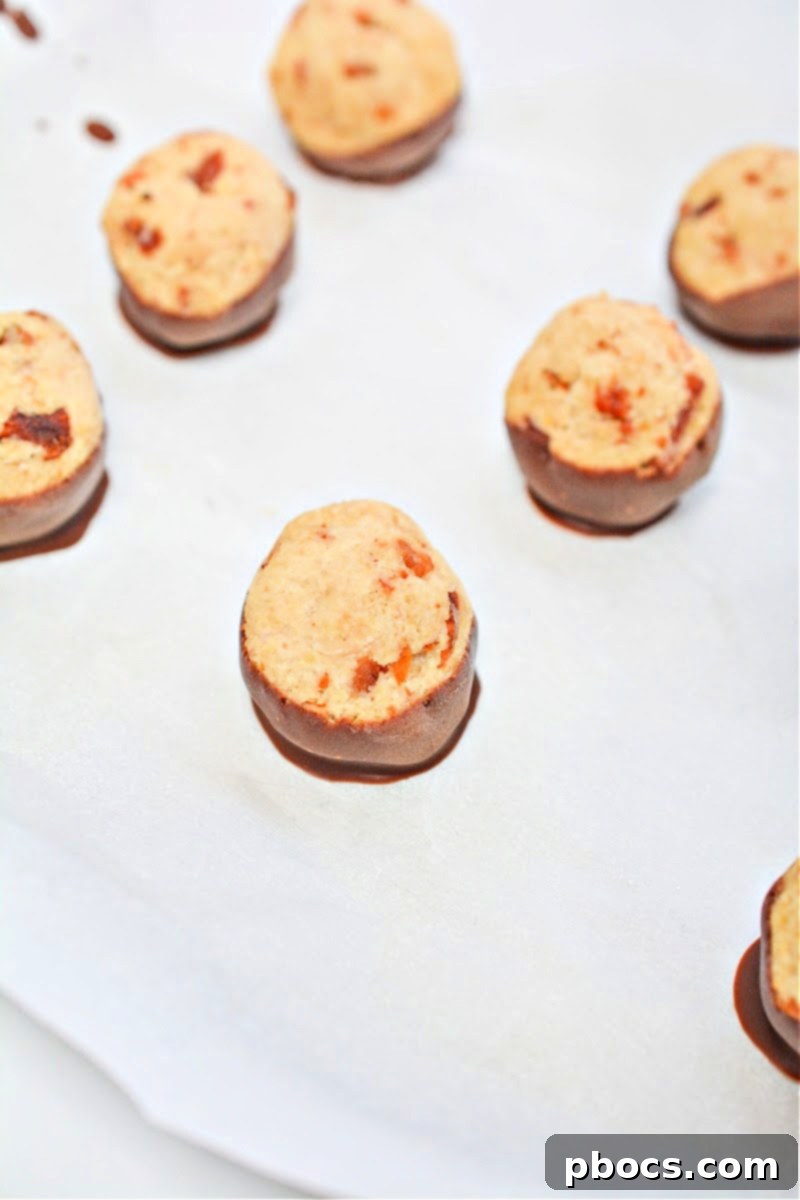 Keto Maple Bacon Bites cooling on parchment paper on a baking sheet, showcasing their setting chocolate.