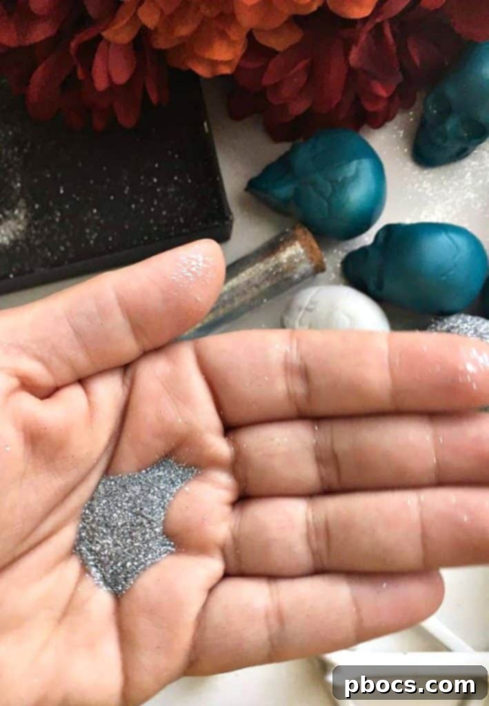 A skull covered in adhesive spray being placed into a shoe box filled with glitter.