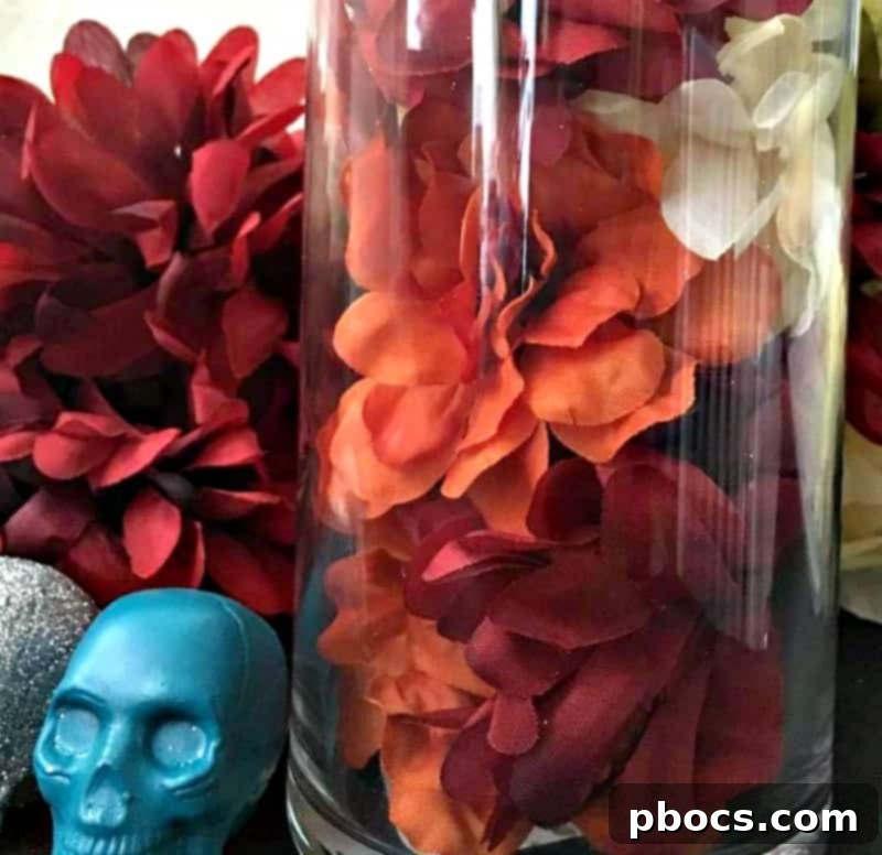 A clear glass vase partially filled with artificial flowers and inverted glitter skulls, forming a vibrant centerpiece base.