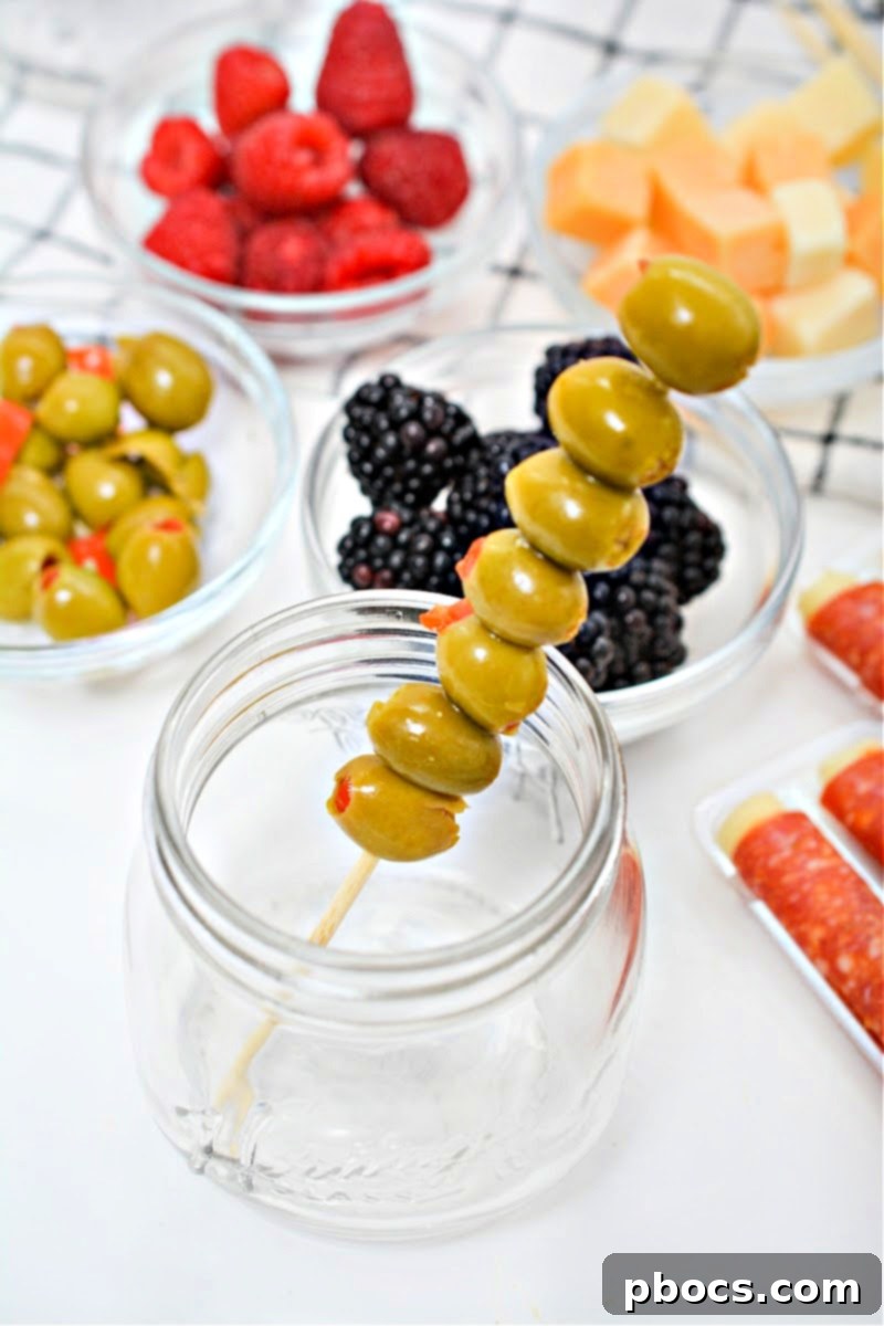 A skewer of green olives in a mason jar.