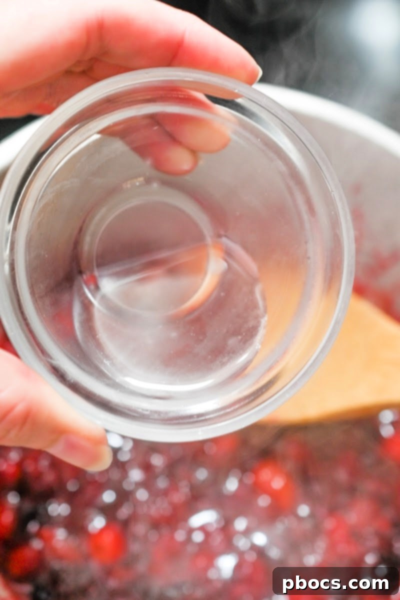 Adding orange extract to the simmering low-carb cranberry sauce mixture.