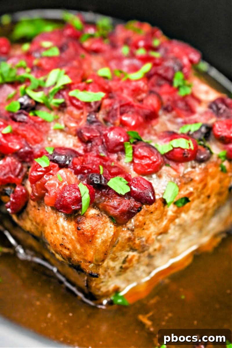 Perfectly cooked Keto Crockpot Cranberry Pork Loin Roast on a serving platter, ready for carving.