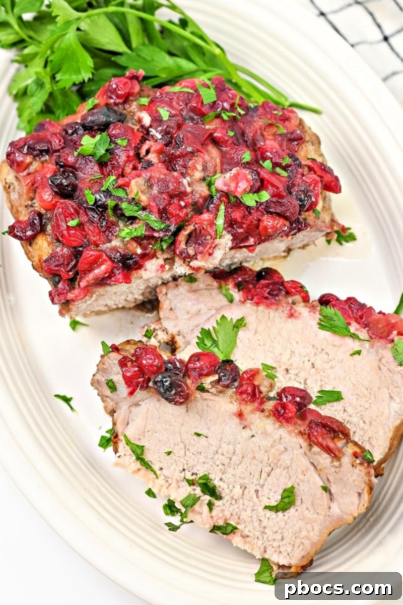A slice of Keto Cranberry Pork Loin served with roasted asparagus and other low-carb sides.