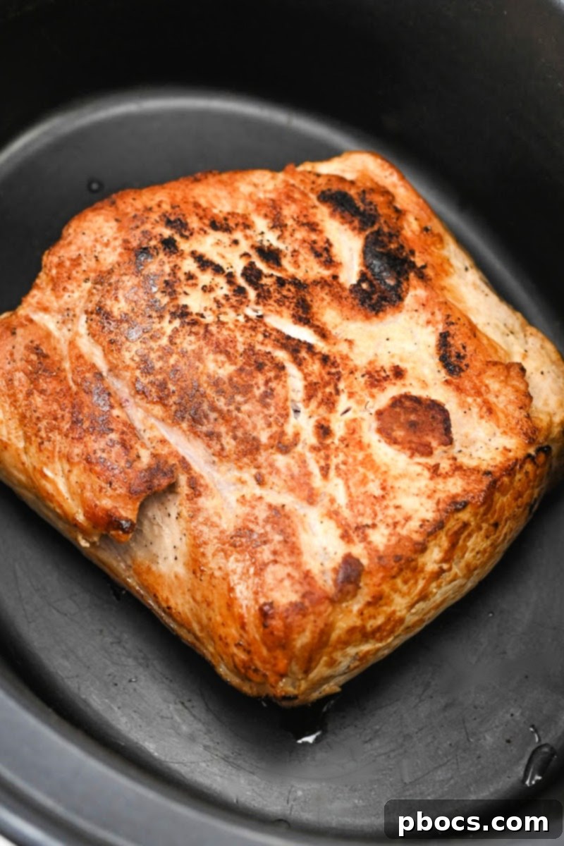 Searing a pork loin roast in a skillet with olive oil over medium-high heat.
