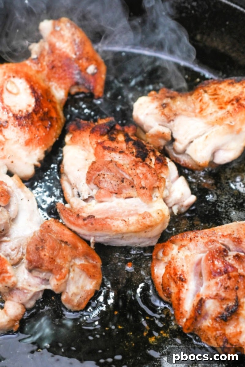 Keto Honey Garlic Chicken with Green Beans 9 Chicken thighs being seasoned with olive oil, onion powder, salt, and pepper in a skillet.